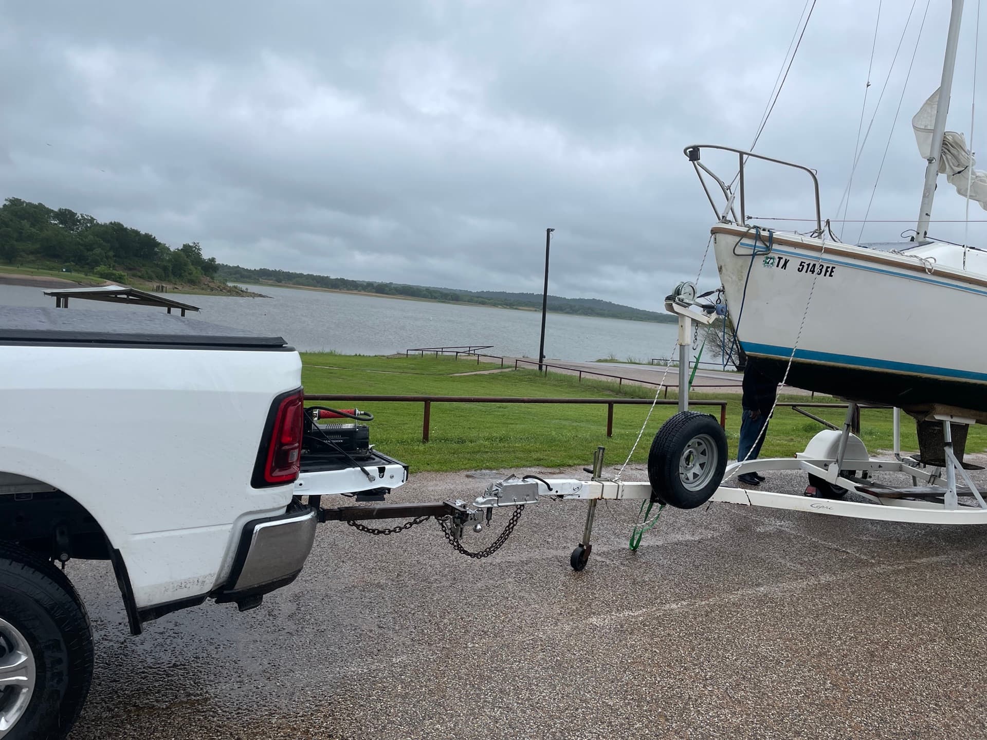 Pickup truck hitched to a sailboat on a trailer at a lakeside lot